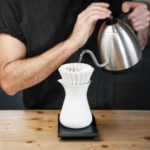 This picture is showing how pour over coffee is made. It shows the reigning World Coffee Roasting Champion Felix Teiretzbacher brewing coffee with the white Mindful Design Coffee Brewer.